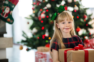 Girl sitting on the floor holding christmas gift smiling