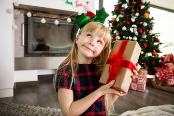 Young girl holding christmas gift looking away thinking