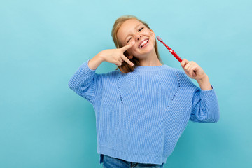 attractive european girl holding a toothbrush in her hands on a light blue wall