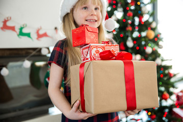 Young happy girl holding lot of christmas gifts
