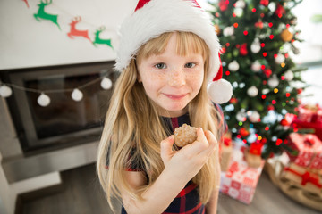 Young girl in santa hat eating gingerbread