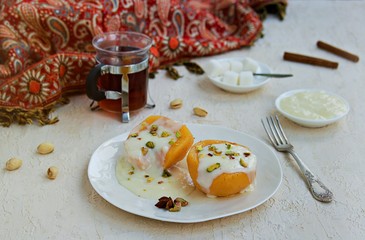 Dessert of stewed quince in syrup, poured with custard on a white plate on a light concrete background. Healthy desserts. Turkish cuisine.