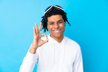 Young African American man with snowboarding glasses showing an ok sign with fingers