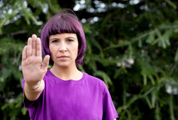Angry woman with in purple showing the hand palm saying STOP