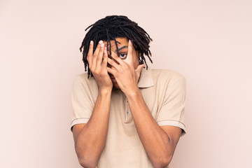 Young African American man over isolated background covering eyes and looking through fingers