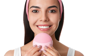 Young woman using facial cleansing brush on white background, closeup. Washing accessory