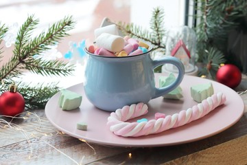 A cup of drink with marshmallows, Christmas decor, illumination on a wooden windowsill, the concept...