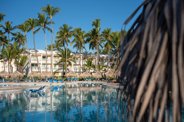 Beautiful tropical beach front hotel resort with swimming pool, sun-loungers and palm trees during...