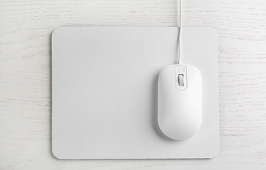 Modern wired optical mouse and pad on white wooden table, top view - Powered by Adobe