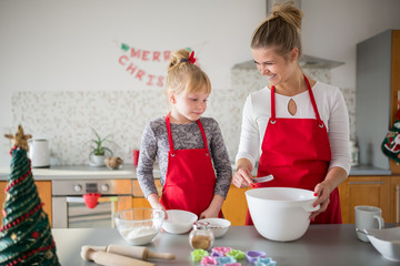 Happy mom teaching her daughter making cookies