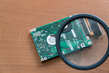 Magnifing glass is enlarging specific areas on a integrated circuit oard fused in  computers .