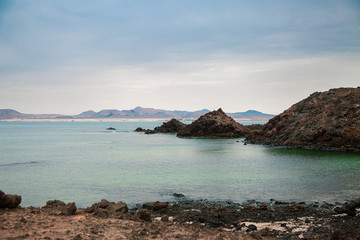 Playa de rocas en una isla con oc&eacute;ano y cielo nublado