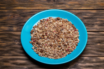 Muesli flakes in blue plate on wooden background