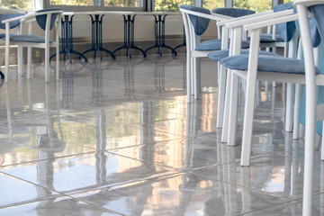 Carolina blue and white tables, chairs on a terrace. White tile floor. Copy space. 