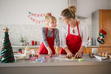 Happy mother and daughter cutting out shapes from dough