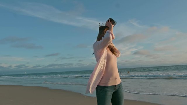 Woman taking VR glasses off and looking at the ocean