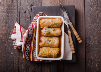 Meat in cabbage rolls in a white plate  with  sauce on wooden background.  Asian cuisine top view. Russian food