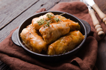 Meat in cabbage rolls in a black pan with  sauce on wooden background.  Asian cuisine top view