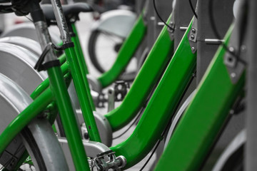 Street transportation green hybrid rent bicycles with electronic form of payment for traveling around the city stand in row on rental network parking lot waiting for cyclists to make bike trip.