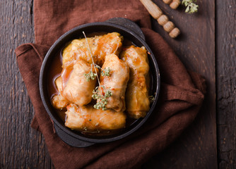 Meat in cabbage rolls in a black pan with  sauce on wooden background.  Asian cuisine top view