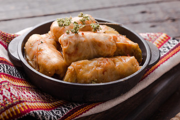 Meat in cabbage rolls in a black pan with  sauce on wooden background.  Asian cuisine top view