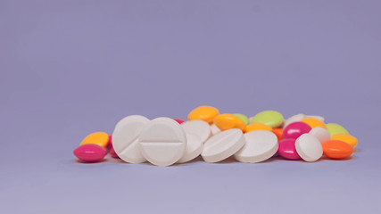 Various multicolor pills lying on purple background