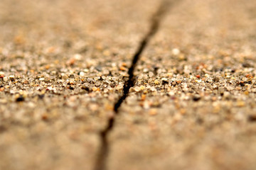 Textured sand plaster, close-up, with a deep crack.