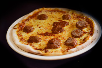 Meatball pizza served on plate, dark background