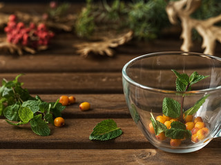 Useful herbal tea with sea buckthorn and ginger. Glass cup with mint leaves and sea buckthorn. Close-up.