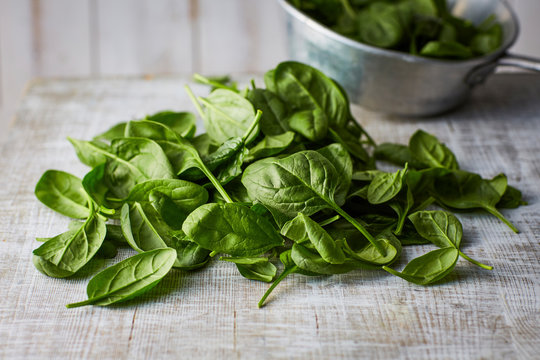 Fresh spinach leaves on wood, colander