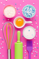 ingredients for baking and kitchen tools on pink background