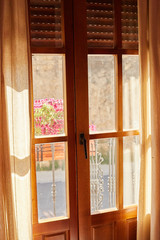The morning sun passes through the transparent curtains of the window, flowers are outside the window. Soft focus