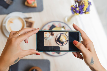 Overhead view of woman in a cafe taking cell phone picture of coffee