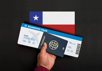 Hand holds passport and boarding pass with flag of Chile
