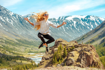 Beautiful girl jumps in yoga pose in mountains