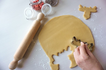 A hand cutting dough with a deer cutter- Making biscuits for christmas and new year holidays- ...