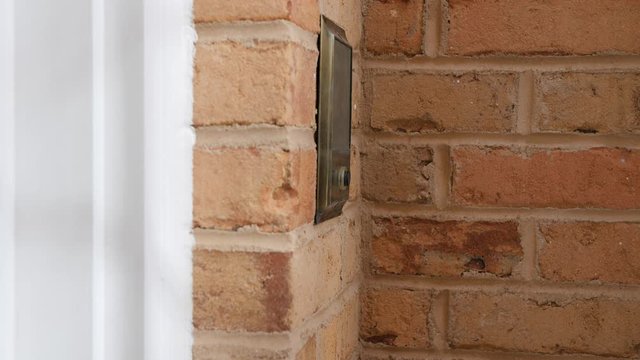 Ringing doorbell with thumb. Male hand pushing home intercom door bell button.
