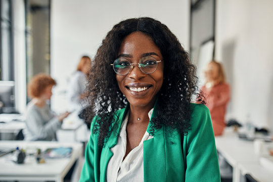 Portrait of a smiling businesswoman in office with colleagues in background