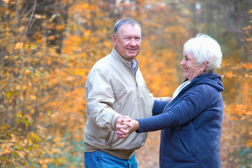 Happy elderly couple dancing in an autumn walk