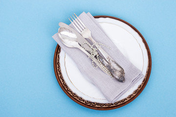 Festive Christmas table setting. Knife, fork, spoon and linen napkin on a blue background. Family holiday concept. Copy space. Flatlay.