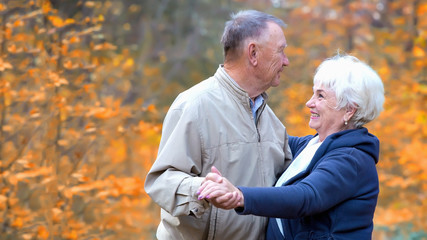 Two seniors dancing in an autumn square