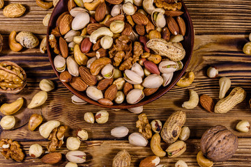 Various nuts (almond, cashew, hazelnut, pistachio, walnut) in ceramic plate on a wooden table. Vegetarian meal. Healthy eating concept. Top view