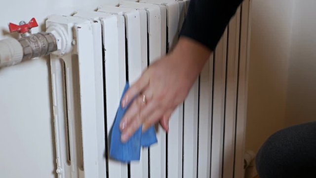 Radiator on a wall.A male hand cleans a heating radiator. Cold, winter, heating, house