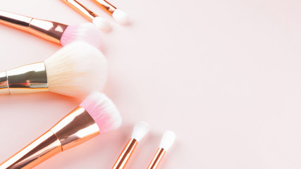 Makeup brushes on pink background. Set of golden makeup brushes, concept. Woman beauty accessory in...
