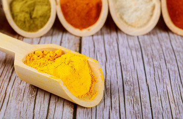 Assortment of powder seasoning in wooden scoops, close up.