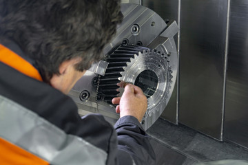 The worker measures the part installed on the machine with a cnc measuring tool.