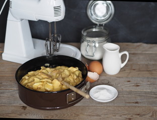 Charlotte muffin dough in the kitchen on a wooden rustic table with ingredients, with a dark blurred background