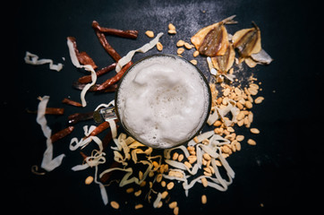 light beer with foam in a glass mug top view. drink on the background of dried fish, colmar, peanuts