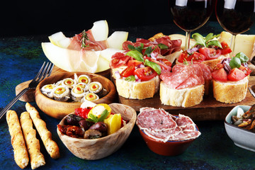Italian antipasti wine snacks set. Cheese variety, Mediterranean olives, seafood salad, Prosciutto di Parma, tomatoes, anchovy and wine in glasses