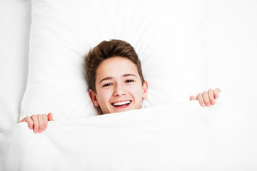 Happy handsome toothy smiling child boy lying bed and resting